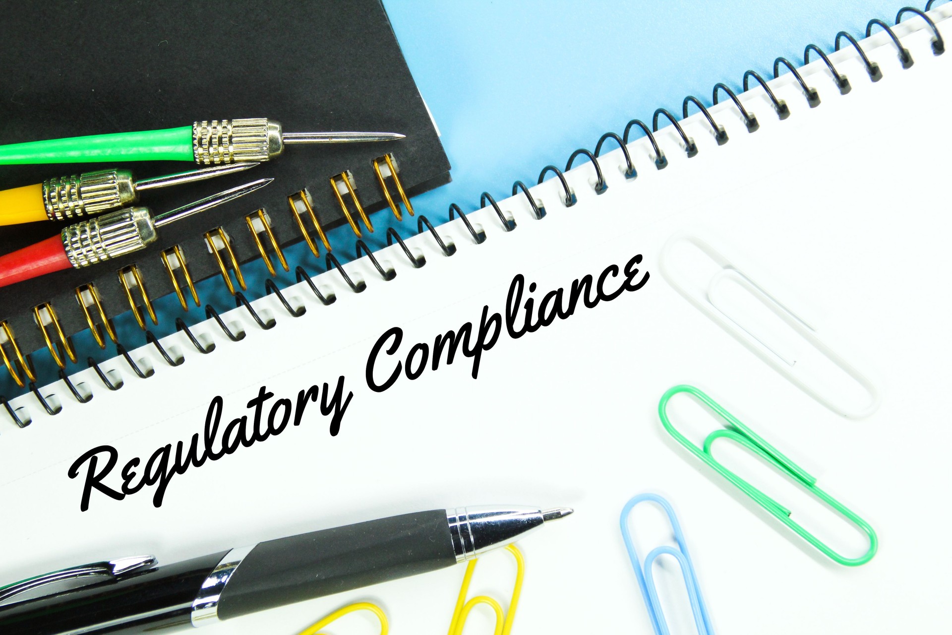 pens, arrows, notebooks, paper clicks and the word regulatory compliance